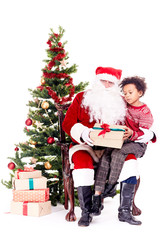 Fototapeta na wymiar Mixed-race little boy receiving Christmas gift from Santa Claus while sitting on his lap