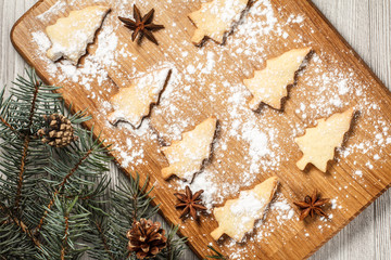 Gingerbread cookies in Christmas tree shape on wooden board sprinkled with powdered sugar