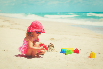 cute little girl play with sand on beach