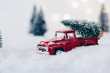 Red toy car carrying Christmas tree.