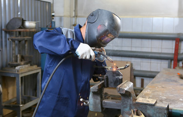 The welder in the mask welds the metal part - obrazy, fototapety, plakaty