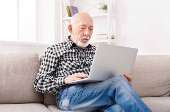 Thoughtful senior man reading news on laptop