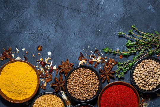 paprika, turmeric, red pepper and other fragrant spices on dark background, top view