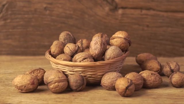 Wallnuts falling into the bowl on the old wooden table