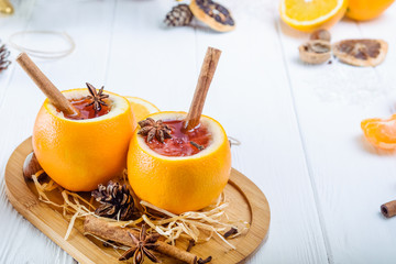Mulled wine - unusual served in orange. Hot winter drink with berries, orange,spices, cinnamon on the wooden table with ingredients and spices. Selective focus. Text space