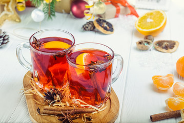 Christmas mulled wine, Hot winter drink with berries, orange,spices, cinnamon in glass cups on the white wooden table with Fir branches, decor, ingredients. Selective focus. Space for text