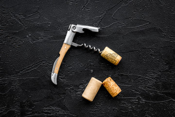 Open wine bottle. Corks and corkscrew on black background top view