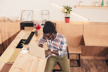 Plakat african american man using laptop at bar counter in coffee shop