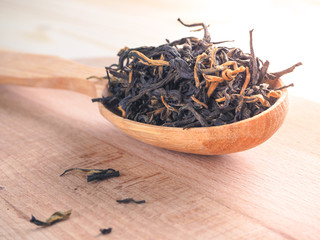 High quality Chinese black tea and a wooden spoon on a wooden table.
