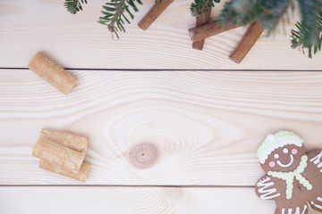 A delicious Christmas composition with a gingerbread man, cookies, wooden twigs and fir tree branches on a light wooden background with fir tree branches and a gingerbread man. Close up. Copyspace