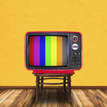 Old television on wood chair in yellow room background.