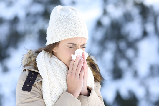 Woman blowing in a tissue in a cold snowy winter