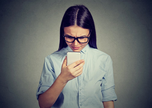 Portrait of upset sad skeptical serious woman talking texting on a phone displeased with conversation