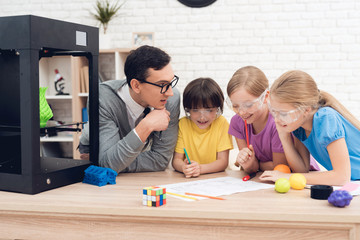 Children print different items on a 3d printer with a teacher.
