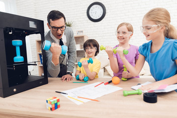 Fototapeta premium Children print different items on a 3d printer with a teacher.