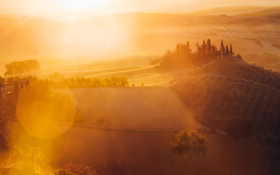 Tuscany, panoramic landscape with famous farmhouse rolling hills and valleys in beautiful golden morning light at sunrise in summer, Val d'Orcia, Italy
