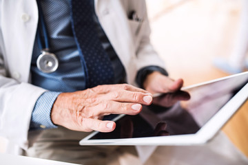 Senior doctor with tablet working at the office.