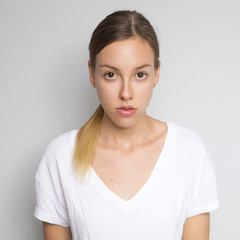 Fototapeta premium Beautiful brunette caucasian woman in white blouse with bright emotions standing on a neutral grey background. Her hands make a gesture. She thoughtful