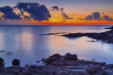 Obraz premium Beautiful sunrise on rocky shore and dramatic sky clouds