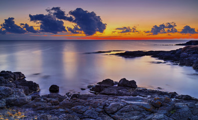 Fototapeta na wymiar Beautiful sunrise on rocky shore and dramatic sky clouds