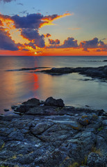 Beautiful sunrise on rocky shore and dramatic sky clouds