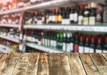 Wood board over blurred alcoholic drinks in supermarket