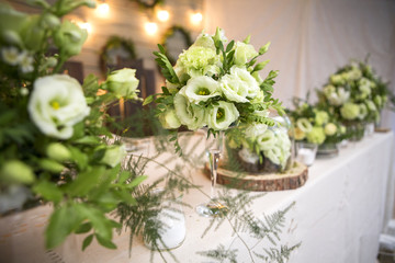 Fresh eustoma roses bouquet composition on a table in a glass vase. Wedding bridal decor. Dim dark sunset light. Romantic mood