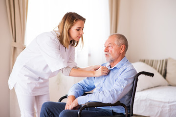 Nurse and senior man in wheelchair during home visit.