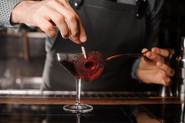 Fototapeta na wymiar Bartender making a red decorated alcoholic drink