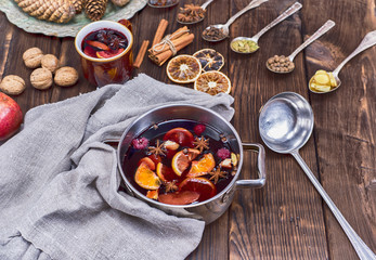 mulled wine in a saucepan and iron spoons with ingredients