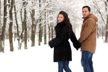 A young couple walk in a winter park
