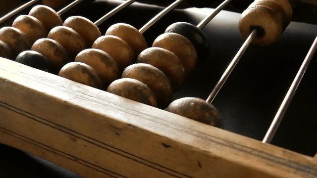 Video shows old wooden abacus. Man is making a calculation