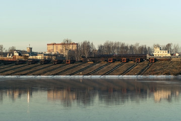 Fototapeta na wymiar slipways with roller-pallets of ship repair yard for river vessels on the shore of the winter canal..