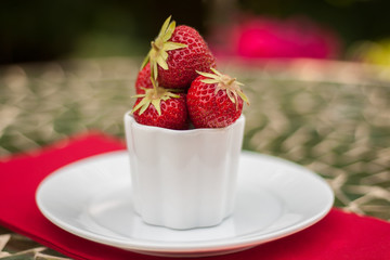 Tiny bowl of red strawberries with shallow DOF