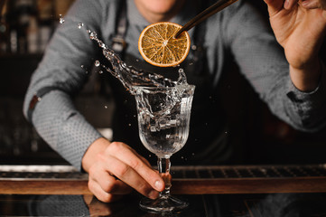 Barman decorating a cocktail glass with splashing drink