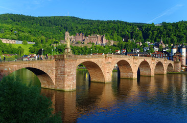 Fototapeta premium Brücke über den Neckar in Heidelberg in Baden-Württemberg in Deutschland bei Sonnenschein mit dem Heidelberger Schloss im Hintergrund