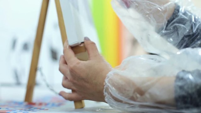 A girl paints a painting using oil paints