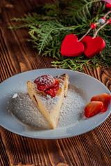 Cheesecake on Valentine's Day with strawberry and hearts on fir and wood background