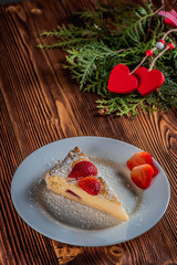 Cheesecake on Valentine's Day with strawberry and hearts on fir and wood background