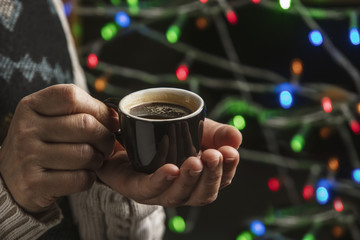 Coffee in woman hands on a Christmas background.