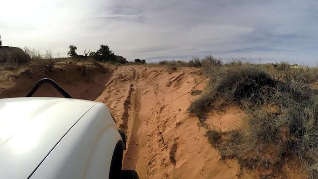 Point of view from truck driving off road through deep sand in the desert near White Pocket Arizona.