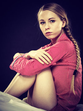 Sad young teenager woman sitting on bed