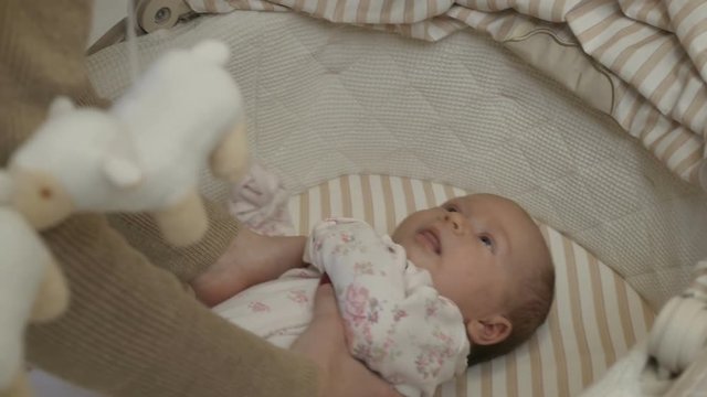 The girl takes the child out of the crib