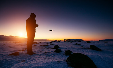 Drone pilot with unmanned aircraft in beautiful sunset ligt. Modern technology and outdoor activity