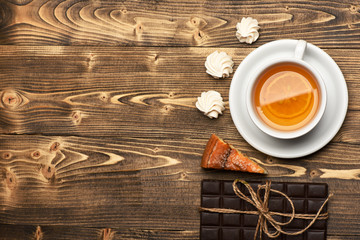 Tea cup with cake, bar of chocolate and meringue