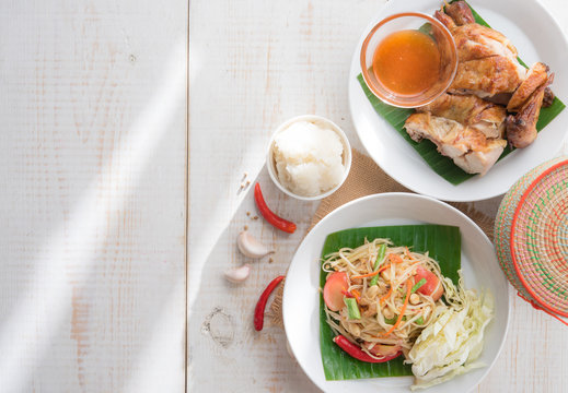 Green papaya salad,Som tum Thai and grilled chicken on wood table,top view
