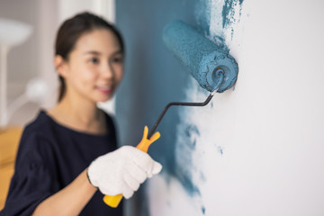 Fototapeta premium Young asian happy woman painting interior wall