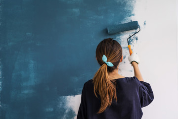 Young asian happy woman painting interior wall with paint roller in new house, Home decoration...