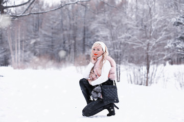 Fototapeta na wymiar Snowy day blonde girl on a walk in a winter park