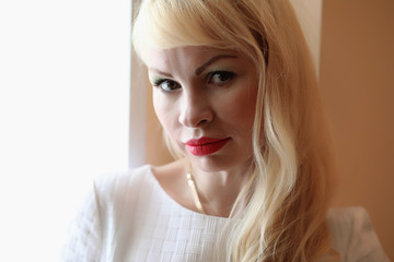 Portrait of a cute girl with blond hair by the window